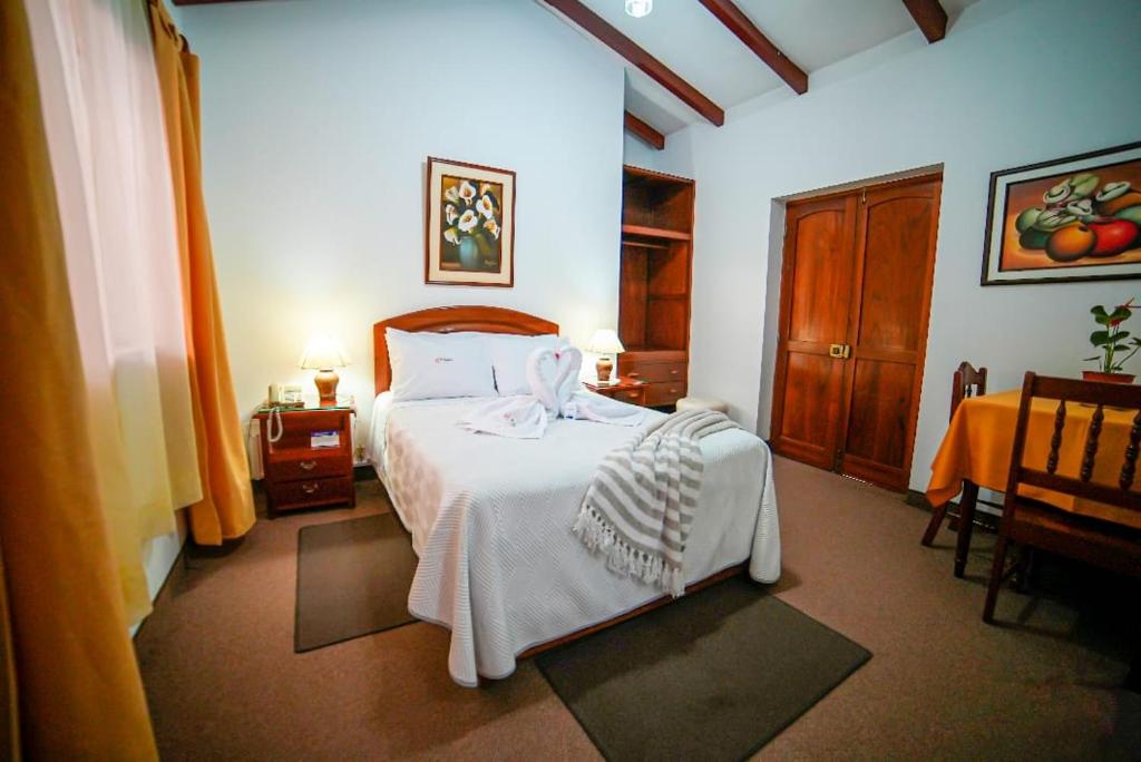 卡哈马卡El Cumbe Inn的一间卧室配有一张带白色床罩的床