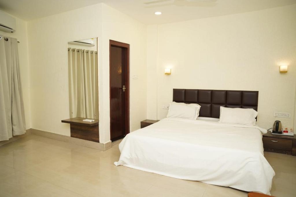 西里古里VIRAMMA RESORT的卧室配有一张白色大床和镜子