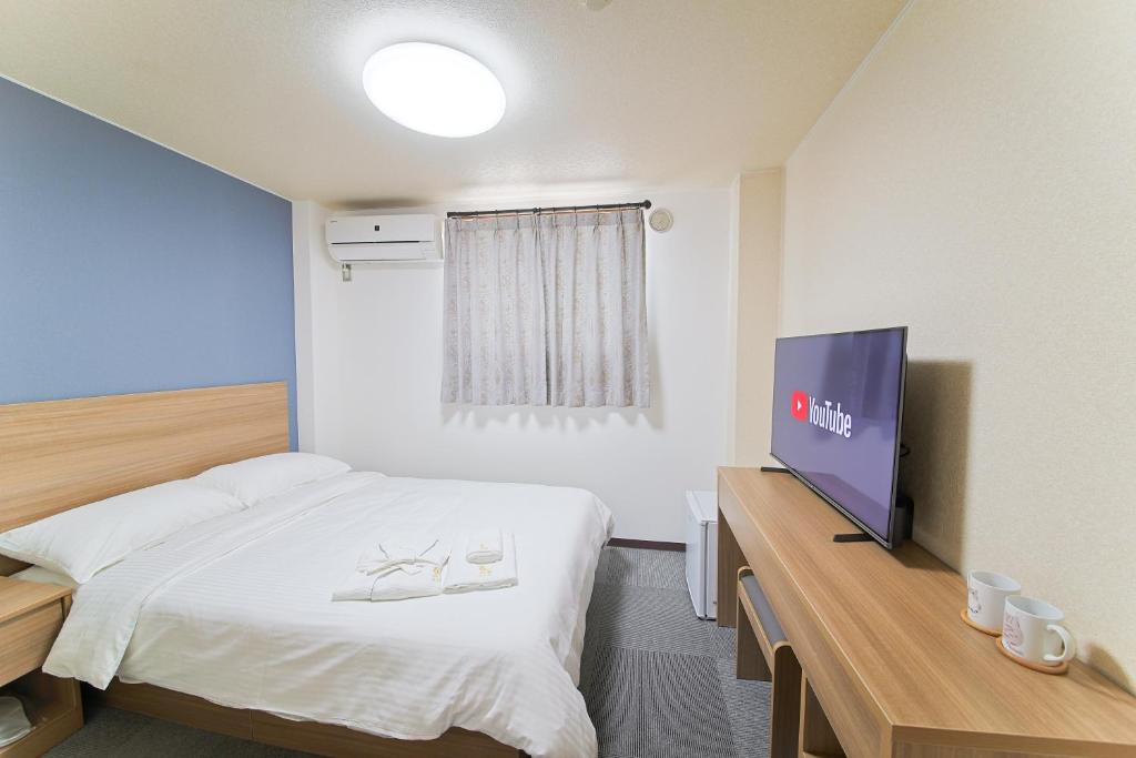 大阪ホテルよしや的配有一张床和一台平面电视的酒店客房
