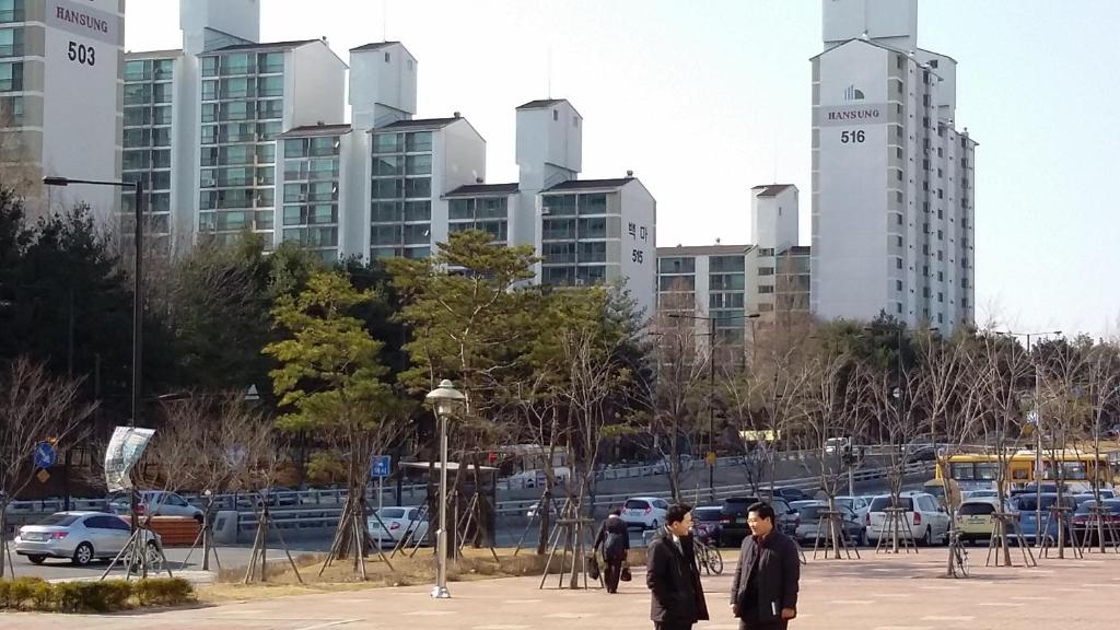 高阳市Goyang City Ilsan Apartment的两个人在停车场里散步,停车场有高楼