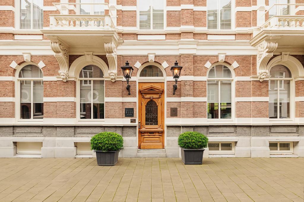 阿姆斯特丹Maison ELLE Amsterdam的一座带木门和两株植物的建筑