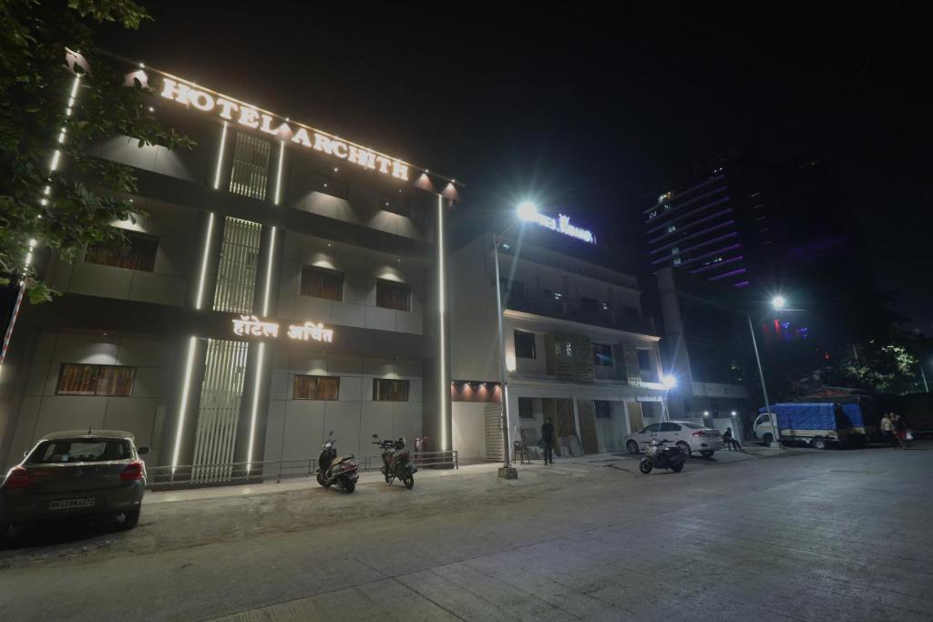 纳威孟买Hotel Archith的一座有摩托车的建筑,在晚上停在它前面