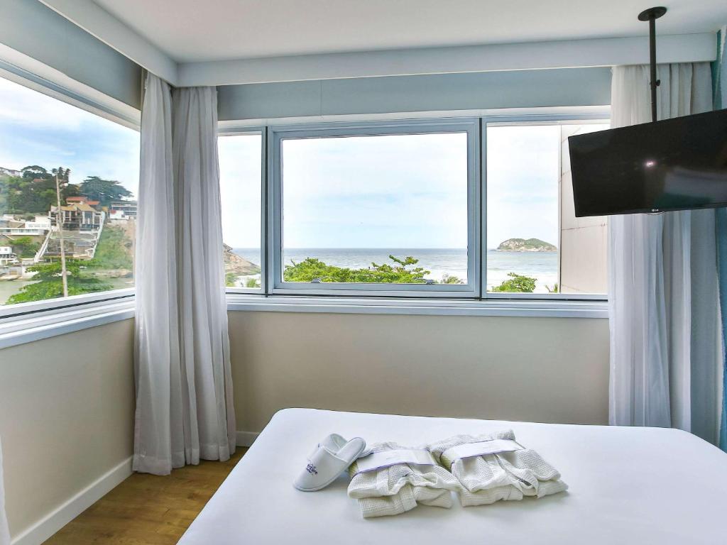里约热内卢Mercure Rio de Janeiro Barra da Tijuca的一间卧室设有一张床,享有海景