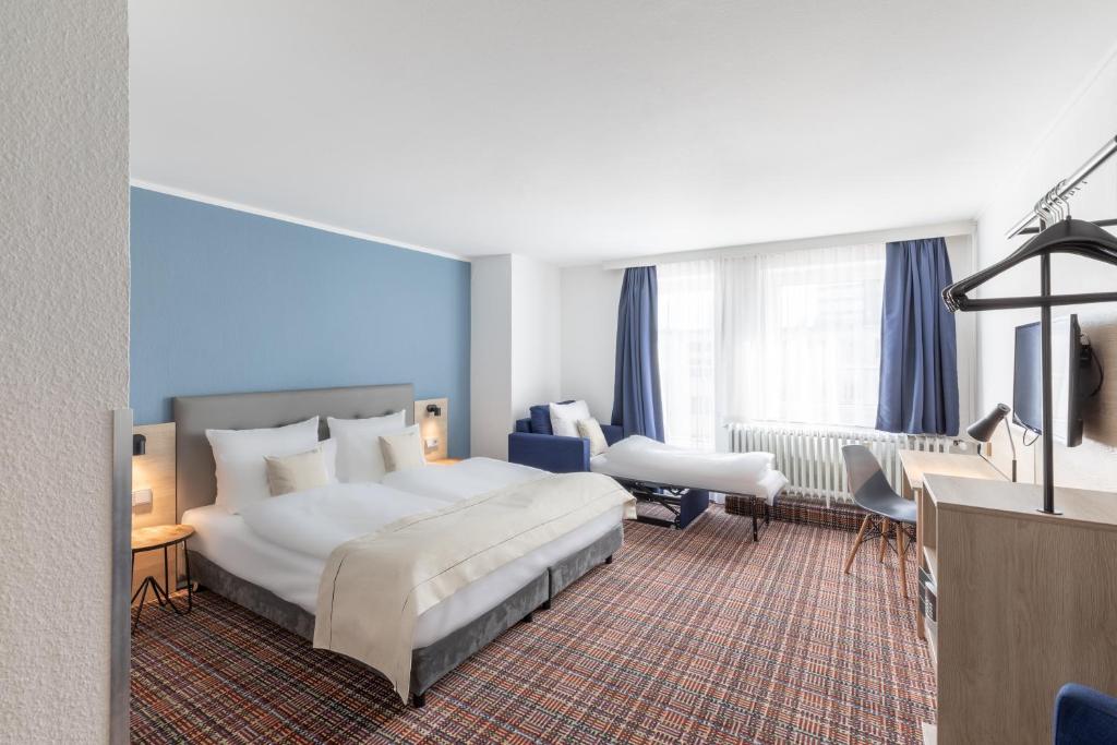 埃森theAmbassador Hotel I Essen City的酒店客房设有一张大床和一张书桌。