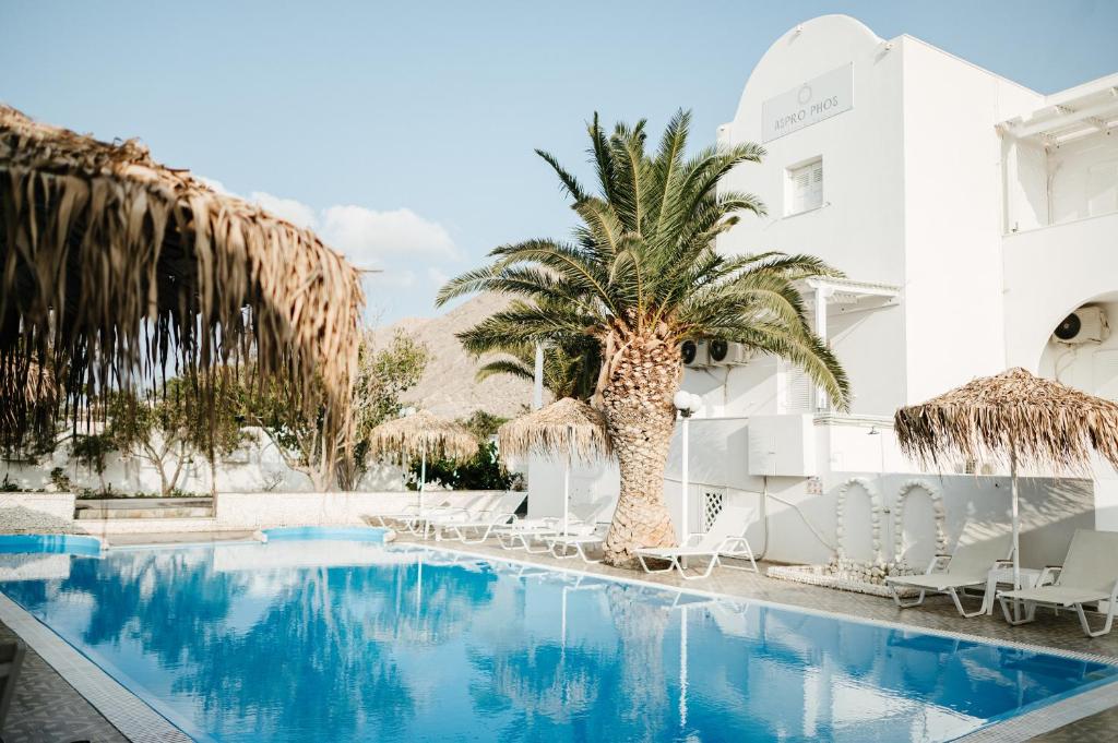 佩里萨Aspro Phos Santorini Hotel的棕榈树和椅子的酒店游泳池