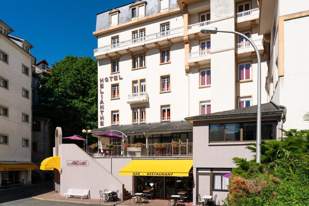 卢尔德Hôtel Hélianthe的一座白色的大建筑,前面设有一间餐厅