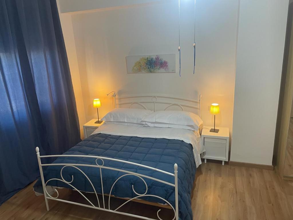 阿普里利亚OLEANDRI SUITE B&B的一间卧室配有一张带蓝色床单的床和两盏灯。