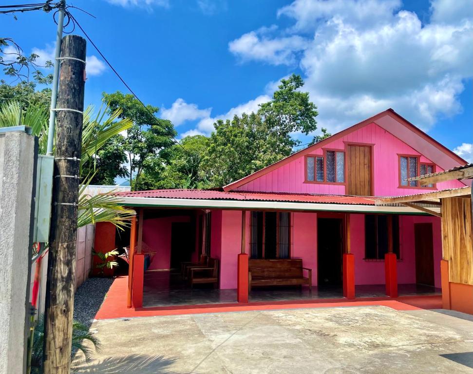 福尔图纳Casa Nativo Spring Arenal的粉红色的房子,前面有长凳