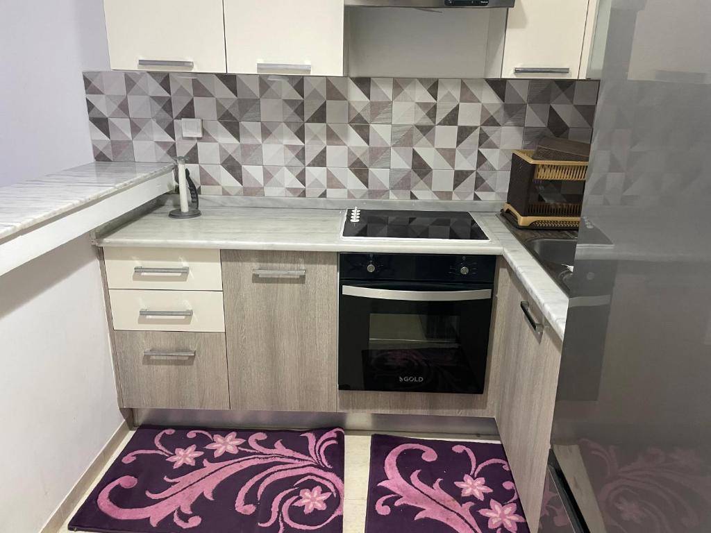 ManūbahMolk的厨房配有炉灶和紫色地毯。