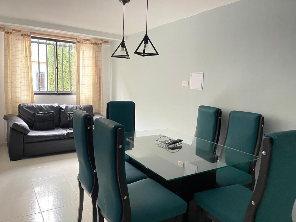 贝约Amplio apartamento en Niquia的一间设有玻璃桌和绿色椅子的用餐室
