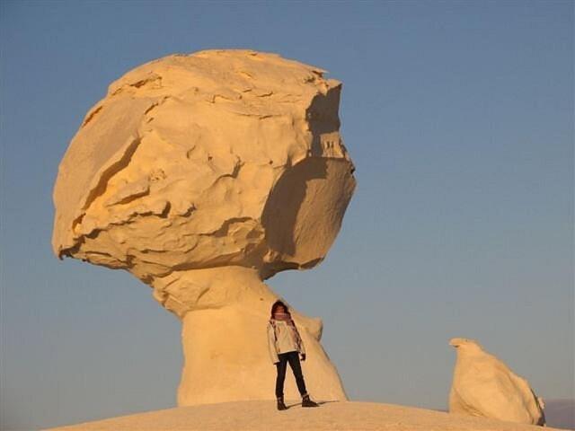 Qasr Al FarafirahWhite desert & Black desert camb的站在大岩石前的人