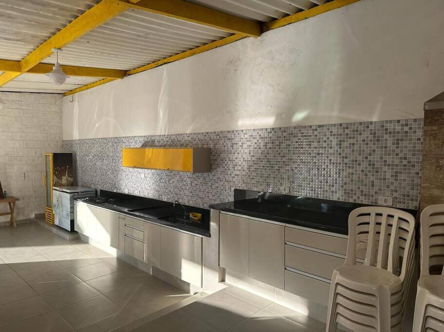 迈里波朗Recanto de Mairiporã的厨房配有黑色柜台和一些椅子