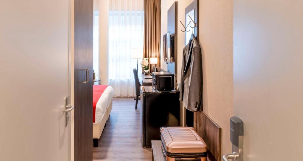 海牙Best Western Plus Plaza Den Haag City Center的客房设有带一张床和一张桌子的卧室