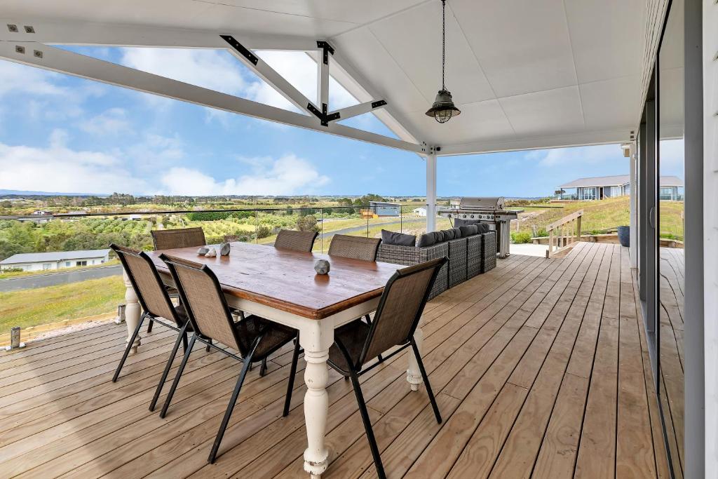 凯塔亚Seaglass - Karikari Peninsula Holiday Home的木制甲板上的木桌和椅子