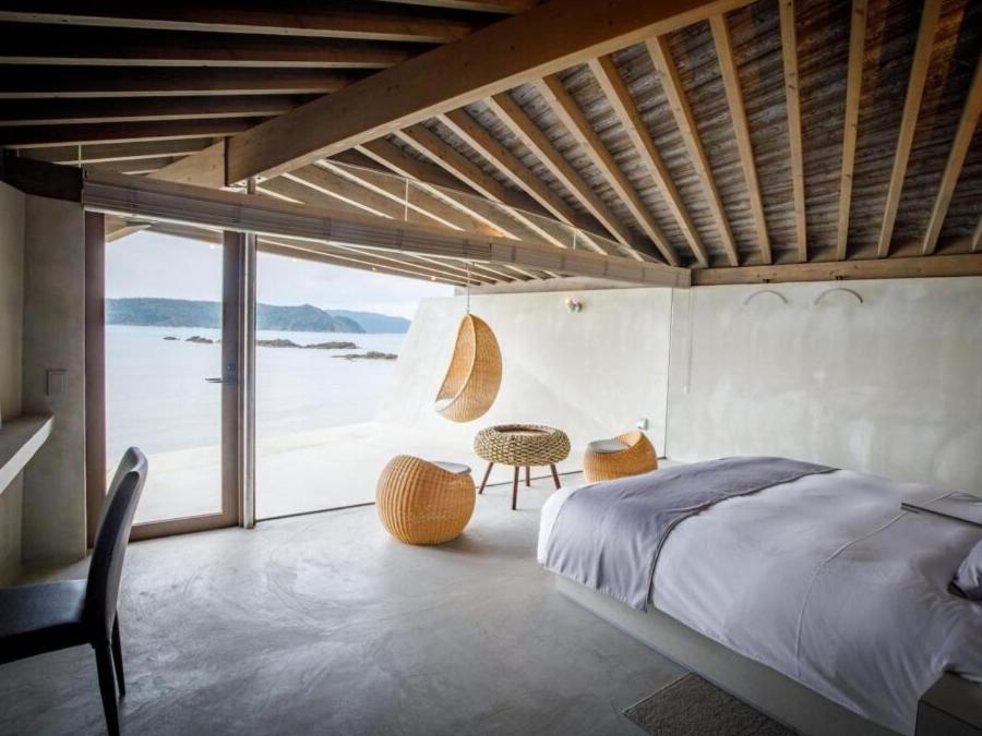 奄美Denpaku The Beachfront MIJORA的一间卧室配有一张床,享有海景