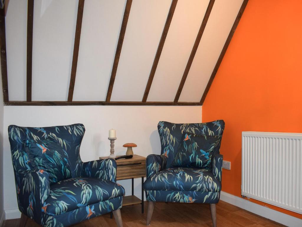 AshburnhamKingfisher Granary的橙色墙壁的房间设有两把椅子和一张桌子