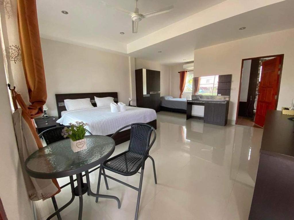 PrakhamPakham Gardens Resort的卧室配有一张床和一张桌子及椅子
