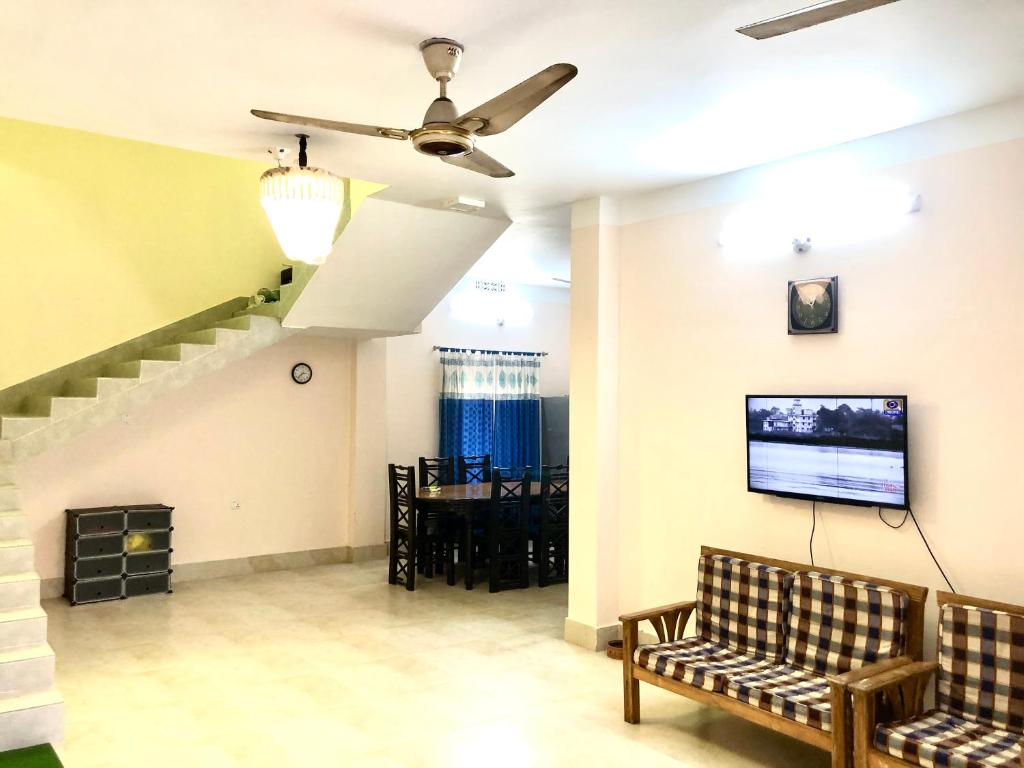 Pirojpur Guest House的客厅配有沙发和墙上的电视