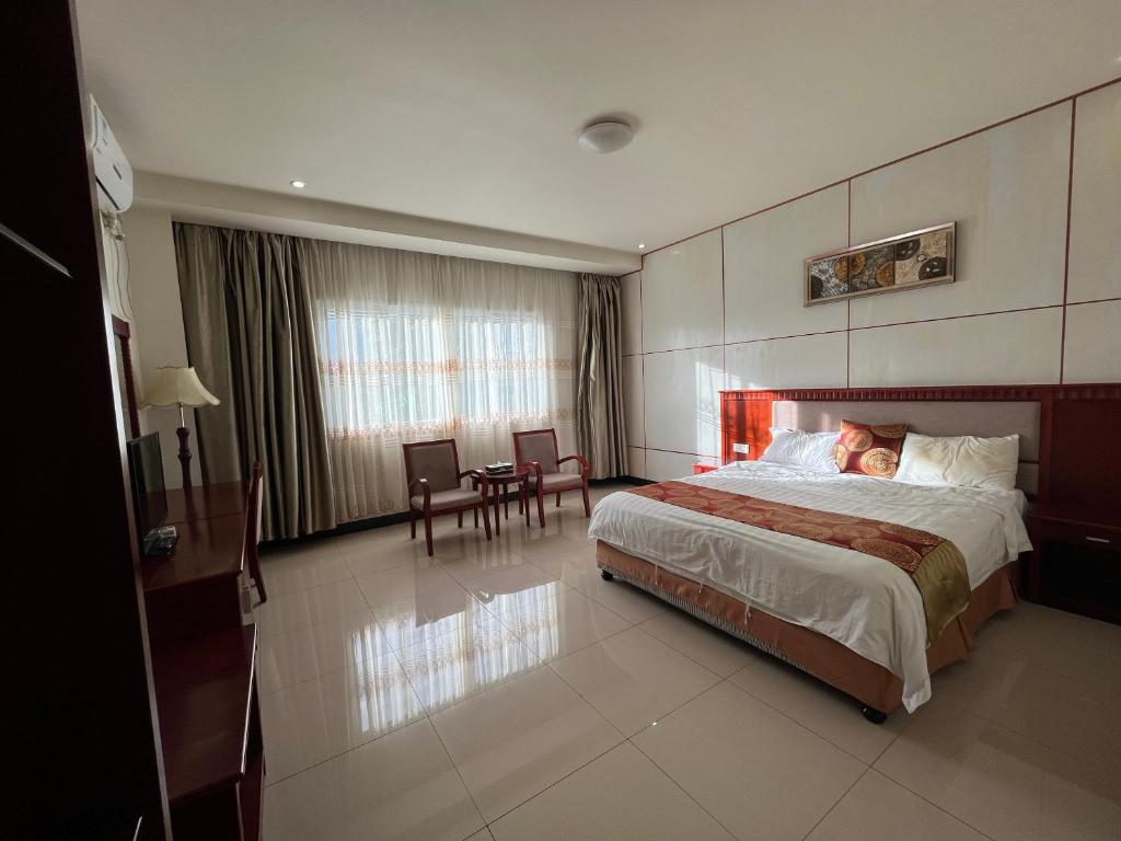 努库阿洛法Meida Hotel的酒店客房带一张床、一张桌子和椅子