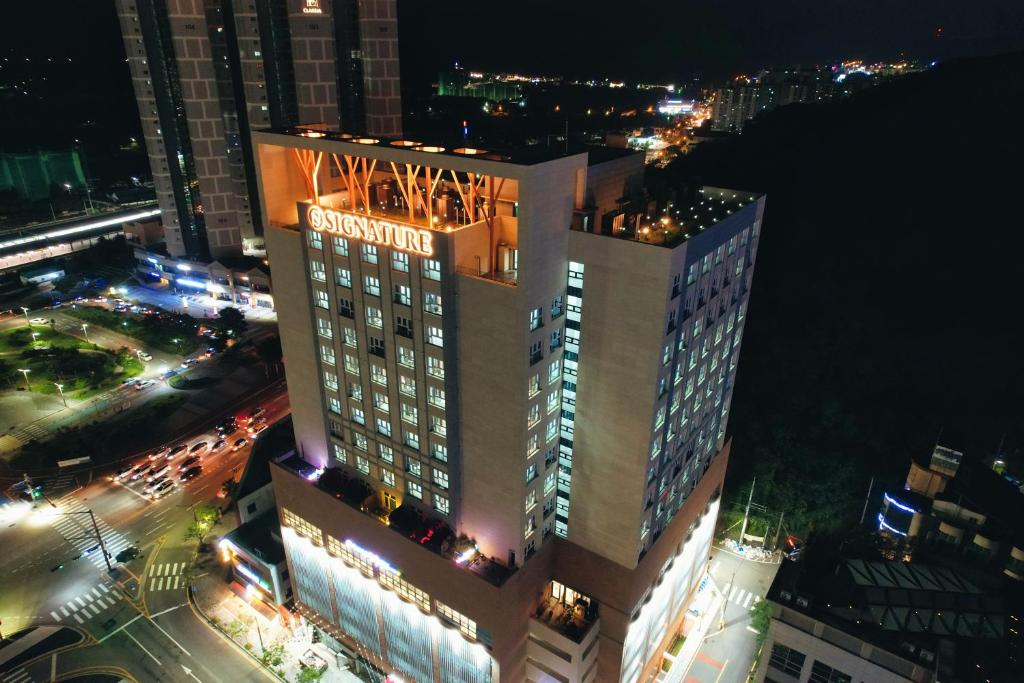 全州市Jeonju Signature Hotel&Residence的一座高大的建筑,晚上有标志