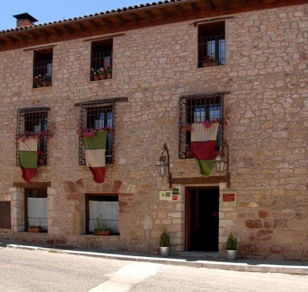 锡古恩萨Los Cuatro Caños的砖砌的建筑,窗户上布满盆栽植物