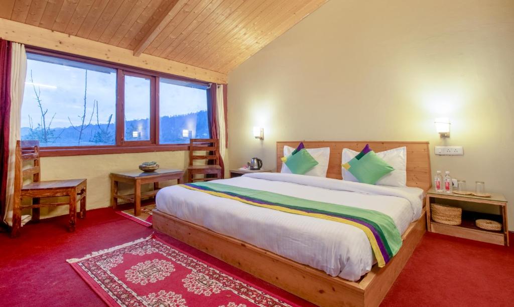 西姆拉Treebo Trend Daak Bangla Retreat With Mountain View的一间卧室设有一张大床和一个大窗户