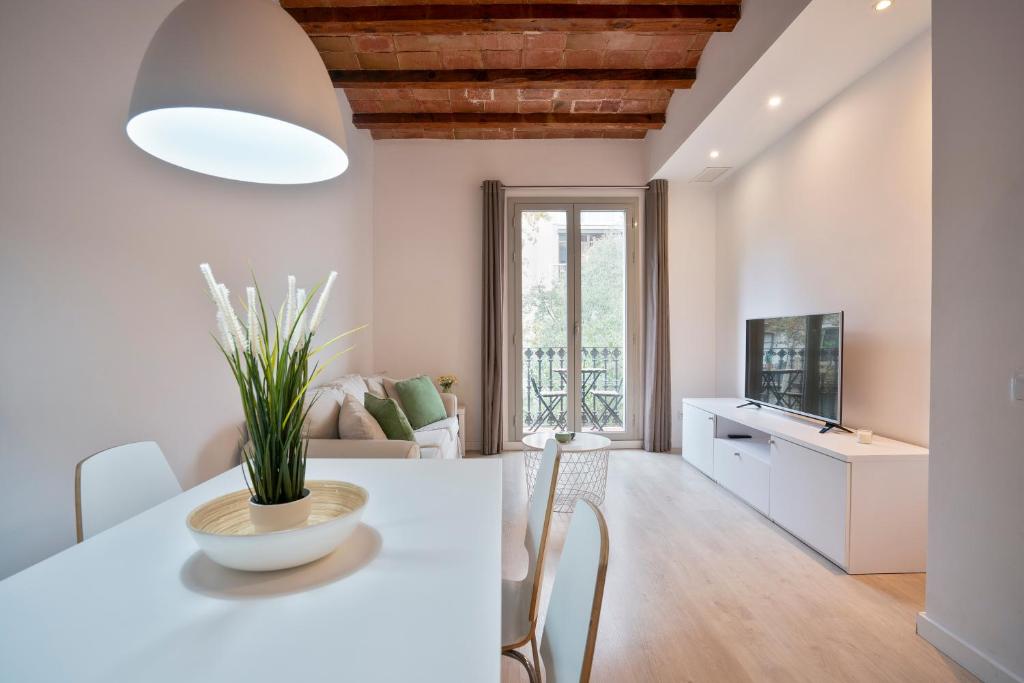 巴塞罗那BcnStop Sant Pau Suites的厨房以及带白色桌椅的起居室。