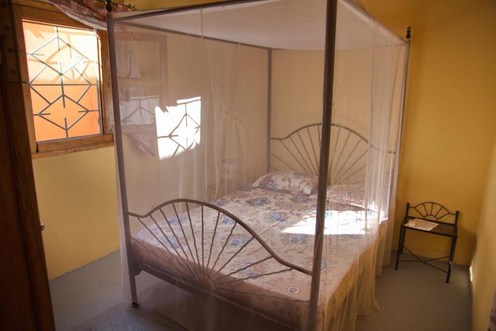 MbodièneAuberge Plein Soleil的一间卧室配有一张天蓬床和窗户