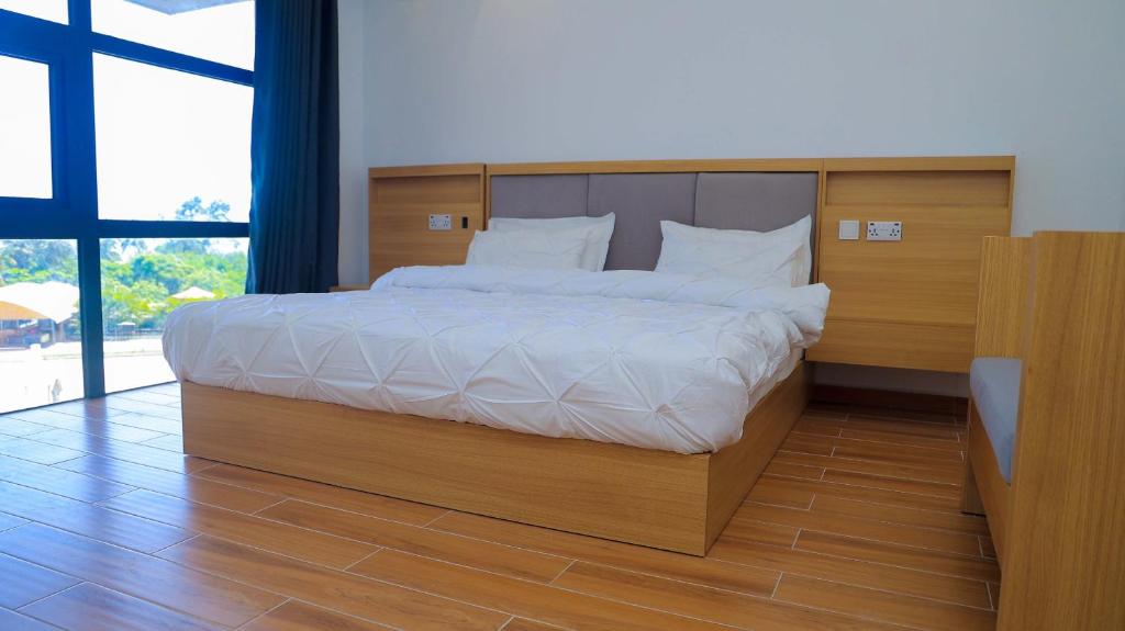 达累斯萨拉姆PALM VILLAGE BUSINESS HOTEL的一间卧室配有一张大床和木制床头板