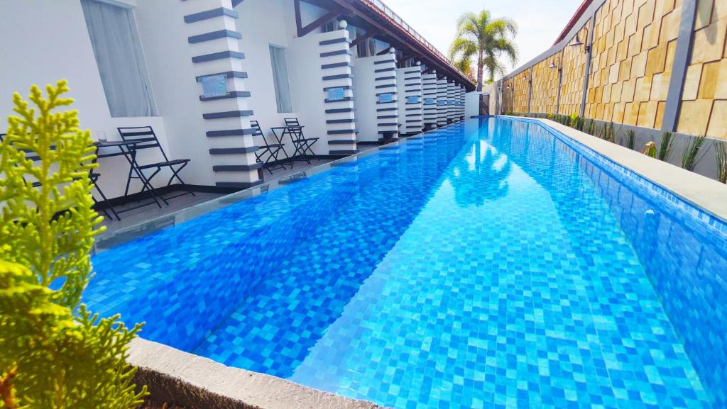 PademabuOdaita Hotel Pamekasan Madura的一座大型蓝色游泳池,位于大楼旁边