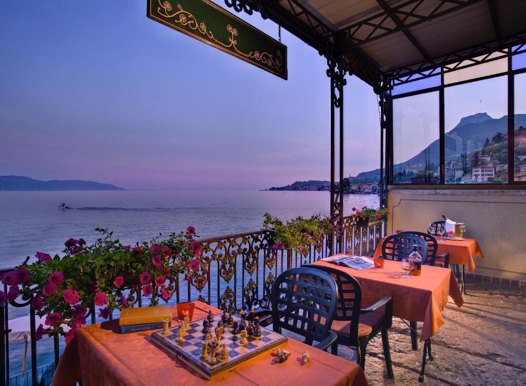 加尔尼亚诺Hotel Garnì Riviera的餐厅设有桌椅,以大海为背景
