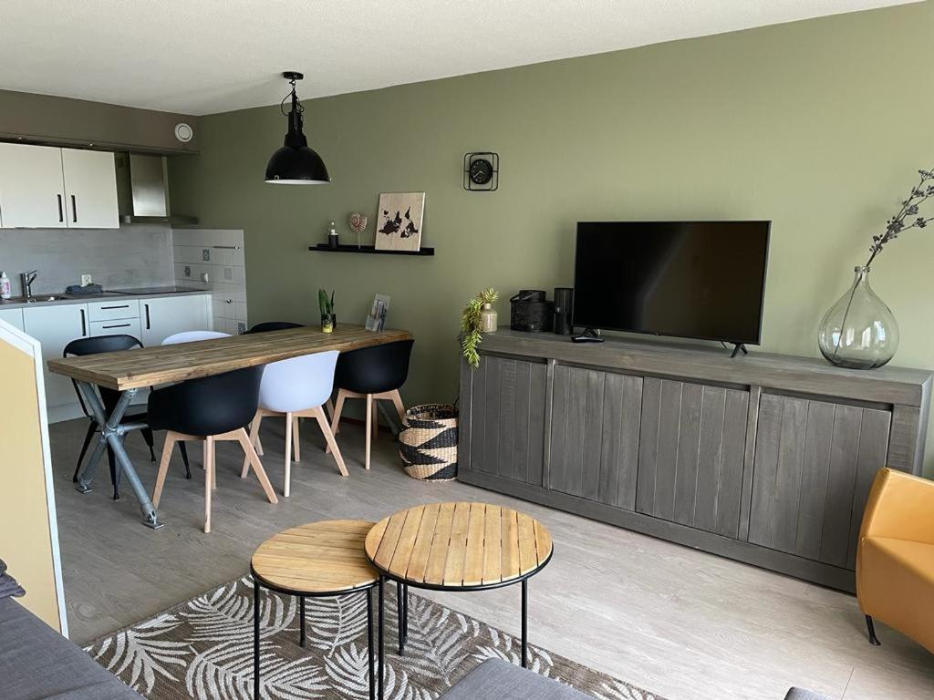 霍勒姆Appartement Senang, Resort Amelander Kaap的一间带桌子的客厅和一间带电视的厨房