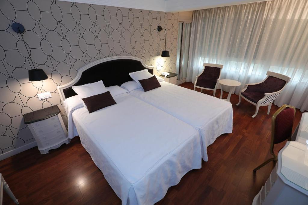 布尔戈斯Hotel Corona de Castilla Burgos的一间卧室配有一张大床和一张桌子及椅子