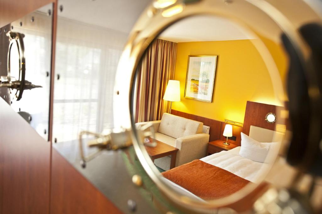 科瑟罗SEETELHOTEL Nautic Usedom Hotel & Spa的酒店客房,配有床和镜子