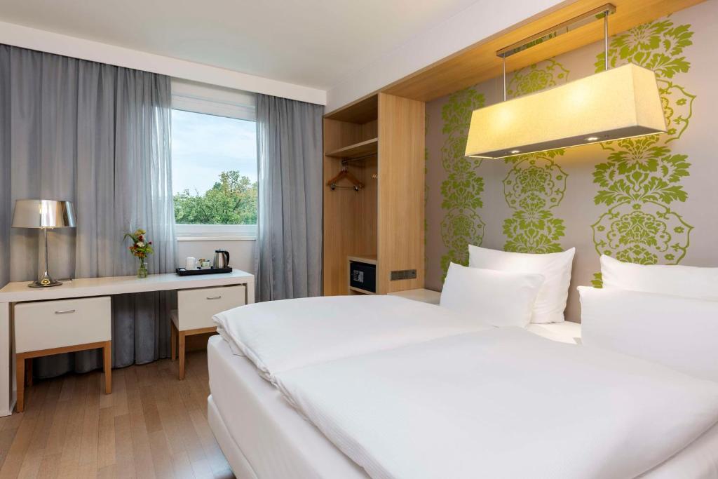 路德维希堡路德维希堡NH酒店的卧室配有白色的床、书桌和窗户。