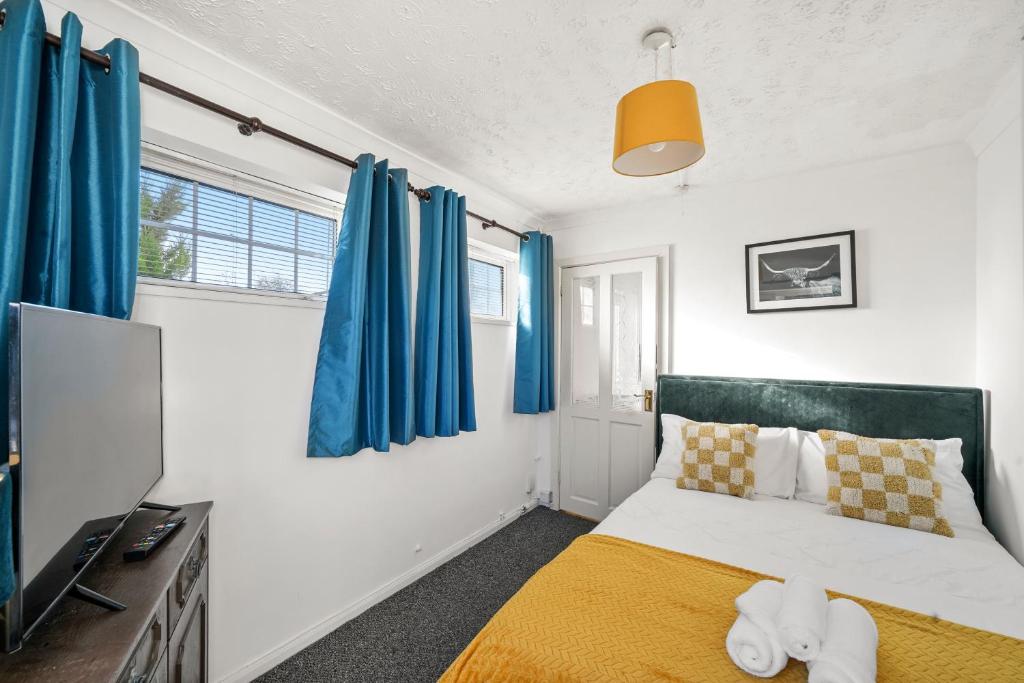 Buckinghamshire1 bedroom flat Aylesbury, Private Parking, Fowler rd的一间卧室配有蓝色窗帘、一张床和电视