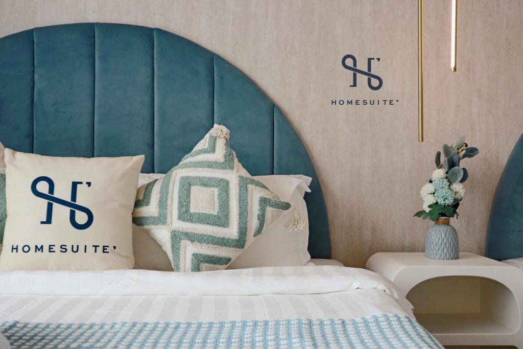 哥打京那巴鲁Homesuite' Home at Aeropod SOVO的一间卧室配有一张带蓝色床头板和枕头的床。