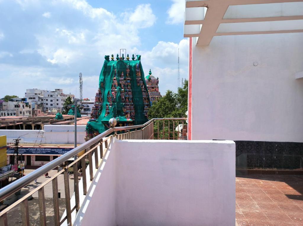 马杜赖LA villa Rani的站在阳台,看到绿色结构的人
