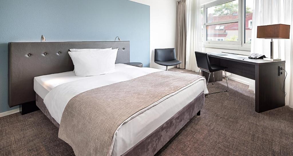 柏林泰格尔柏林胜利皇宫酒店的酒店客房配有一张床、一张书桌和一张书桌。