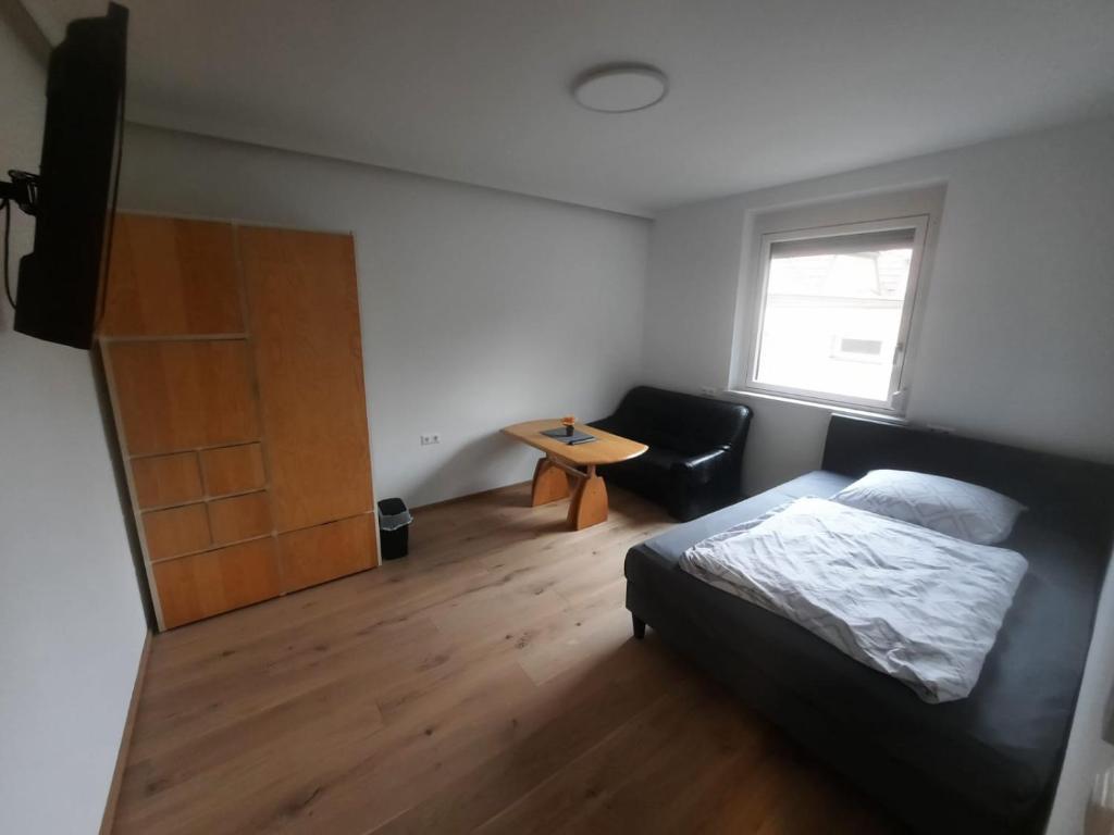 格拉茨Quiet Room with shared kitchen bathroom的一间卧室配有一张床、一张桌子和一个窗户。