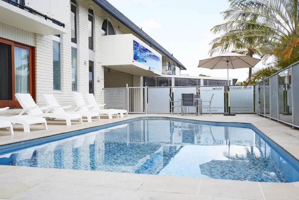 拜伦湾海湾汽车旅馆的一个带白色椅子和遮阳伞的游泳池