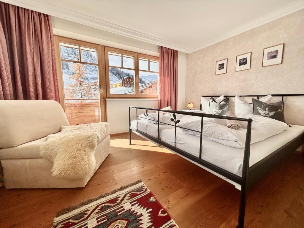 沃瑟姆阿尔伯格Hillside One - Ski-In Ski-Out Apartments am Arlberg的一间卧室配有一张床、一张沙发和一把椅子