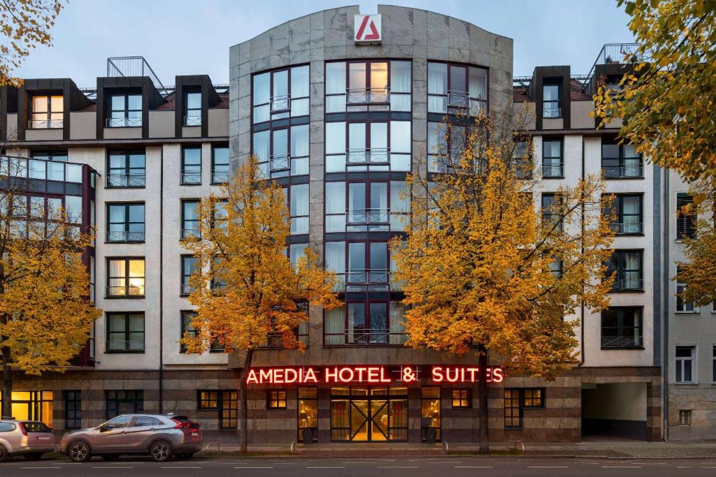 莱比锡Amedia Hotel &amp; Suites Leipzig, Trademark Collection by Wyndham的角形酒店和套房大楼前设有停车位