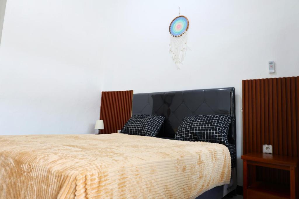 沙努尔Pondok Dete Guesthouse的卧室配有一张床,墙上挂着一个钟