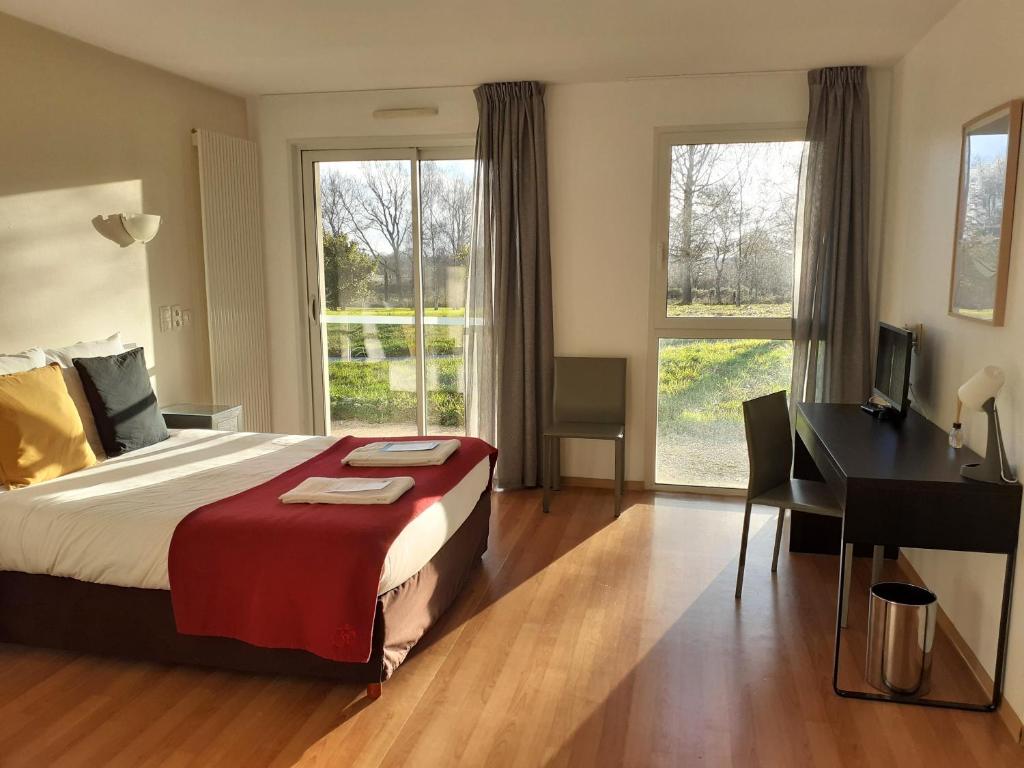 塞科斯La Villa des Golf.e.s的卧室配有一张床、一张书桌和窗户。