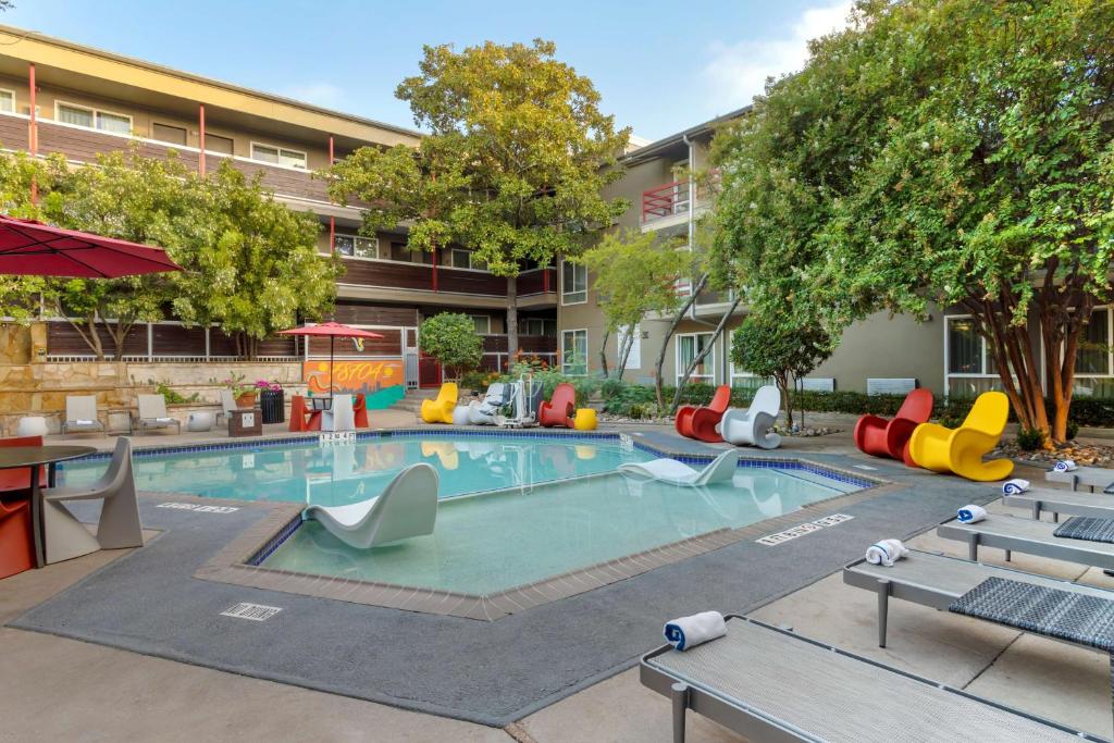 奥斯汀Aiden by Best Western Austin City Hotel的室外游泳池配有五颜六色的桌椅