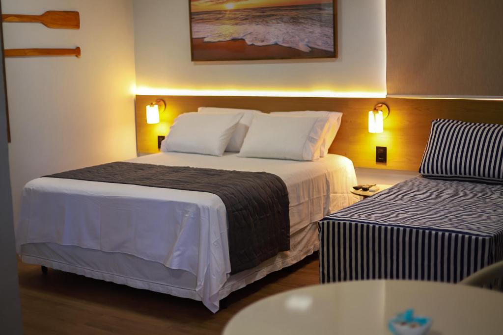 马拉戈日O Azul de Maragogi - Pousada Premium的酒店客房设有一张大床和一张桌子。