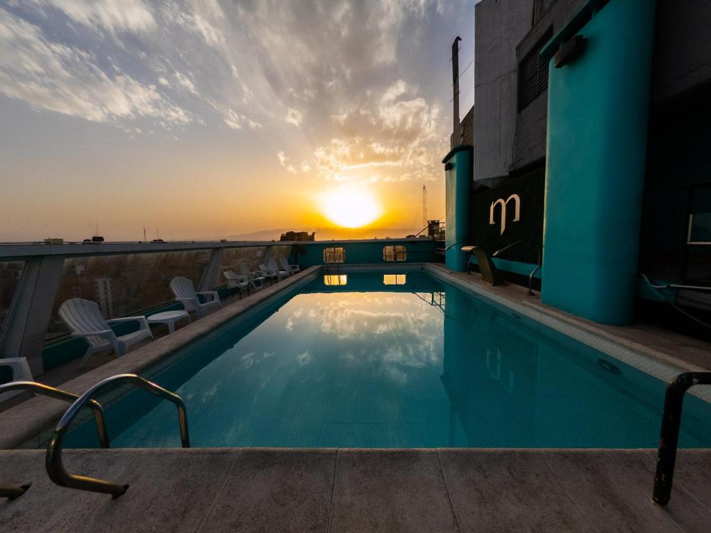 圣米格尔·德·图库玛梅特罗珀尔酒店的一座享有日落美景的建筑屋顶上的游泳池