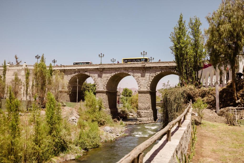 阿雷基帕La Posada del Puente的一条河上的桥梁,上面有火车