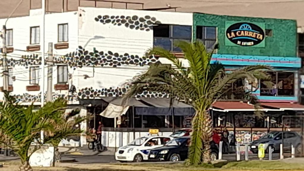 伊基克Hotel La Carreta Playa Brava的白色的建筑,有汽车停在停车场
